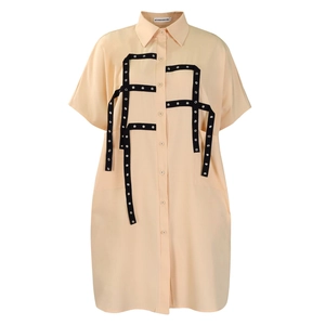 Close-up of apricot shirt dress with black ribbon trim and silver metallic eyelet details
