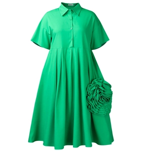 Detail of green shirt dress featuring large 3D floral accent and pleated skirt texture