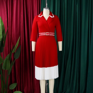 Detailed view of red pleated dress featuring contrast white lapels and elegant gold buckle belt