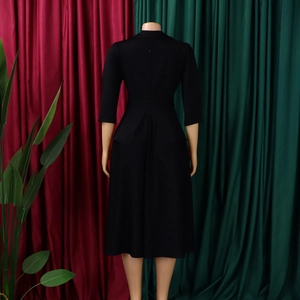 Vue arrière d'une robe midi noire avec manches trois-quarts et silhouette de jupe évasée