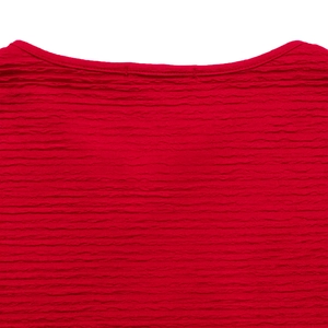 Détail du haut rouge à col rond montrant la texture gaufrée et les coutures nettes