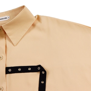 Detail of apricot collared shirt with button closure and black eyelet decorative strap
