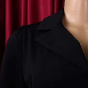 Détail du col tailleur noir et de la couture épaule bouffante sur robe élégante