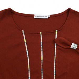 Close-up of elegant round neck with plaid piping and bow on rust red dress fabric