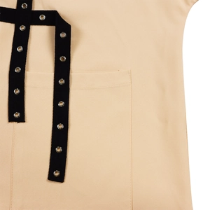 Detailed macro view of beige canvas shirt with black woven straps and silver grommet hardware