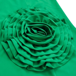 Detailed macro view of 3D bright green fabric rose applique on a sleek satin dress