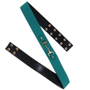 Détail d'une ceinture en toile vert foncé avec boucle mors dorée et œillets