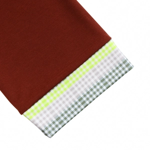Macro shot of dark red ribbed knit fabric featuring green and white checkered cuff details