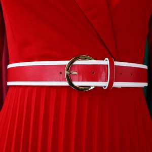 Close-up of red pleated dress featuring a bicolor belt and gold metal buckle detail