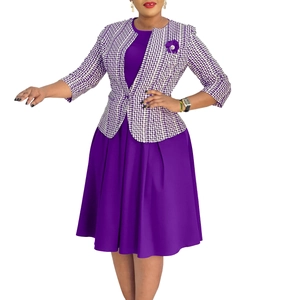 Détail d'une veste en tweed violet avec broche fleurie et robe trapèze assortie