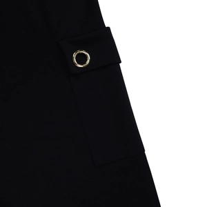 Détail d'une robe noire taille haute montrant une poche à rabat avec un œillet métallique doré