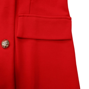 Detailed close-up of a red suit dress with a vintage gold crest button and flap pocket