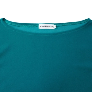Dettaglio dello scollo a barca e dell'etichetta di un abito elegante color ciano