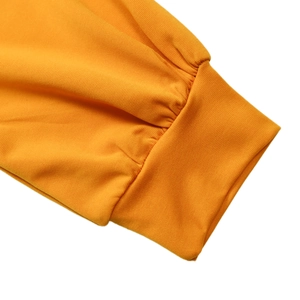 Dettaglio dei polsini a costine su un abito a maniche lunghe in maglia giallo zenzero