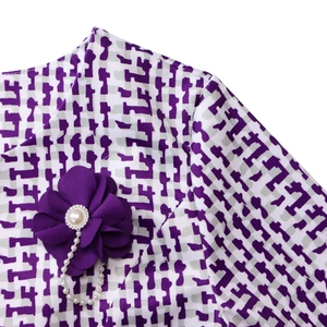 Détail de l'encolure à imprimé africain avec fleur en tissu violet et ornement de perles