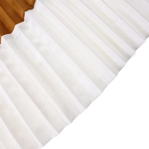 Close-up detail of fine vertical pleats on a white and brown color-block dress