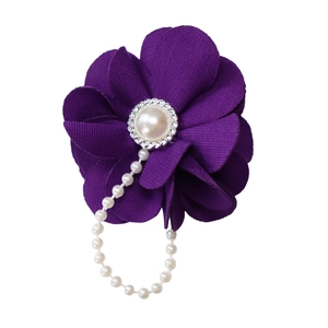 Détail macro d'une broche fleur en tissu violet avec centre perle et chaîne perlée