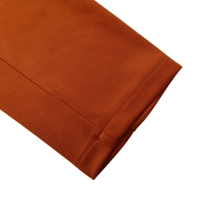 Detailed close-up of refined knit fabric and stitching on caramel orange dress sleeve