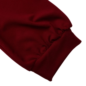 Dettaglio dei polsini a coste su un abito bordeaux elegante con trama in maglia