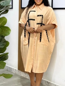 Relaxed apricot shirt dress with turn-down collar and black eyelet ribbon details
