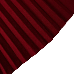 Dettaglio macro del tessuto plissettato rosso vino con pieghe e texture vellutata