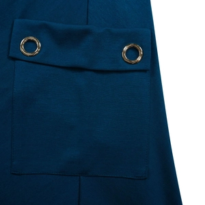 Détail macro d'une robe tissée sarcelle foncée avec une poche à rabat et œillets dorés
