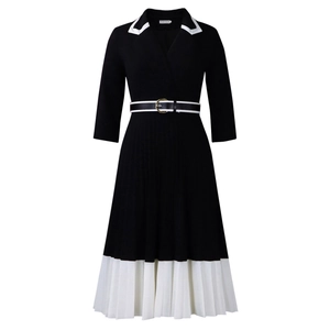 Detailed view of black dress featuring a gold buckle belt and white pleated hem contrast