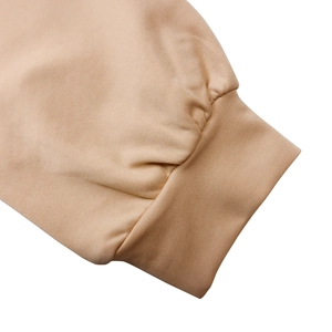 Dettaglio ravvicinato dei polsini a coste di un abito albicocca con trama twill pregiata