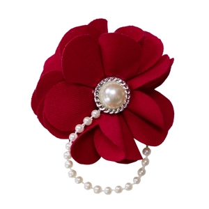 Détail d'une broche fleur en tissu bordeaux avec texture côtelée et perle centrale