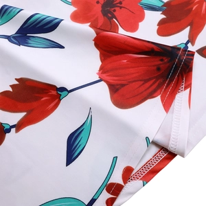 Vue macro d'imprimé floral rouge sur tissu blanc avec feuilles bleu-vert et ourlet soigné