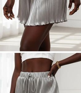 Detail of silver metallic pleated shorts with elastic drawstring waist and vertical texture