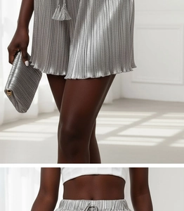 Detail of silver metallic pleated high waist shorts with drawstring and matching clutch bag