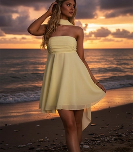 Détail d'une robe bustier jaune en mousseline avec foulard sur fond de plage au coucher du soleil