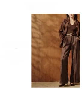 Detailed view of wide-leg trousers with a brown leather belt and square metal buckle