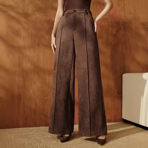 Detail of high-waist dark brown suede wide-leg trousers with elegant front pleat design