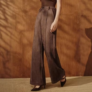 Detail view of high-waist suede wide-leg trousers featuring vertical front seam and drapes