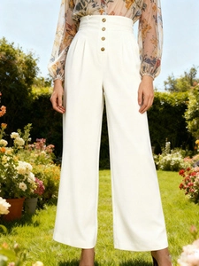 Detail of high waisted wide leg trousers featuring vintage gold buttons and pleats