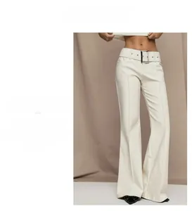 Detail view of high waisted wide leg beige trousers with an oversized silver buckle belt