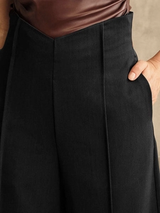 High-waist black wide-leg trousers with V-shaped waistband and elegant pintuck details