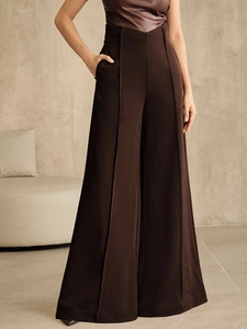 Close-up of high-waisted dark brown wide-leg trousers with elegant pleated details