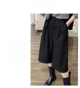 Detail view of black high-waisted wide-leg cropped trousers with stylish waist pleats