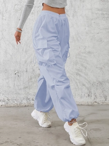 Detail of light blue high-waisted cargo pants showing large utility pockets and drawstrings