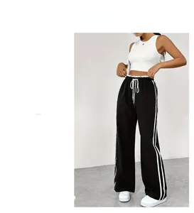 Détail de pantalon de sport noir large avec bandes blanches et taille à cordon