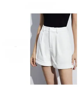 Detailed view of high-waisted white A-line shorts featuring pleats and rolled hems