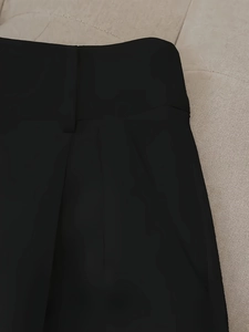 Front waist detail of black high-waisted shorts with belt loops and elegant pleats