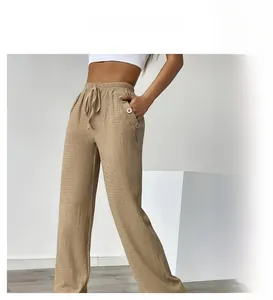 Detail of high waisted wide leg trousers with drawstring and decorative buttons on pocket