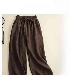 Detail of loose-fit brown wide-leg linen trousers with drawstring elastic waistband