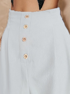 High-waisted light blue textured skirt featuring decorative gold buttons and pleated fabric