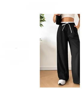 Detail view of black straight-leg trousers with double-layered waist and white drawstrings
