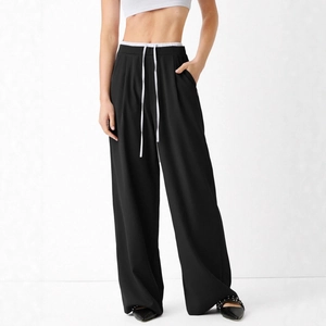 Detail of high-waisted black straight pants with white contrast waistband and drawstring